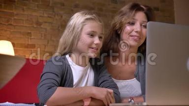年轻<strong>母</strong>亲和女儿在笔记本电脑上一起看电影并讨论<strong>情节</strong>的特写镜头